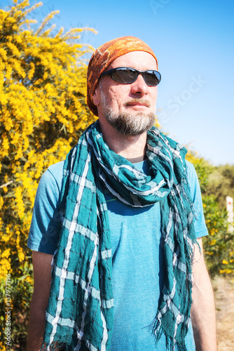 Portrait of bearded man who traveling hitchhiking, on background of yellow flowers