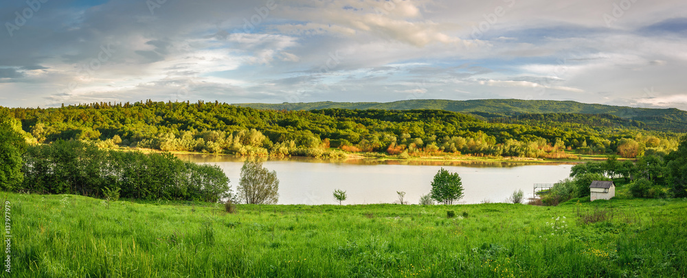 Beautiful landscape. The lake is between the green meadows and mountains.