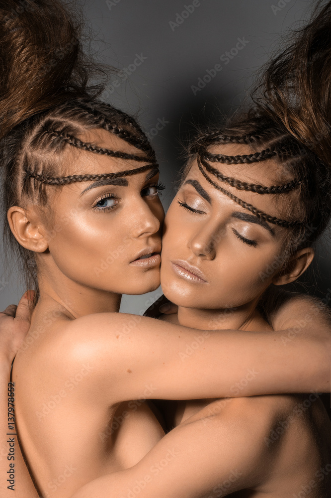 Portrait of gorgeous twins in studio over grey background together Portrait of gorgeous twins in studio over grey background together