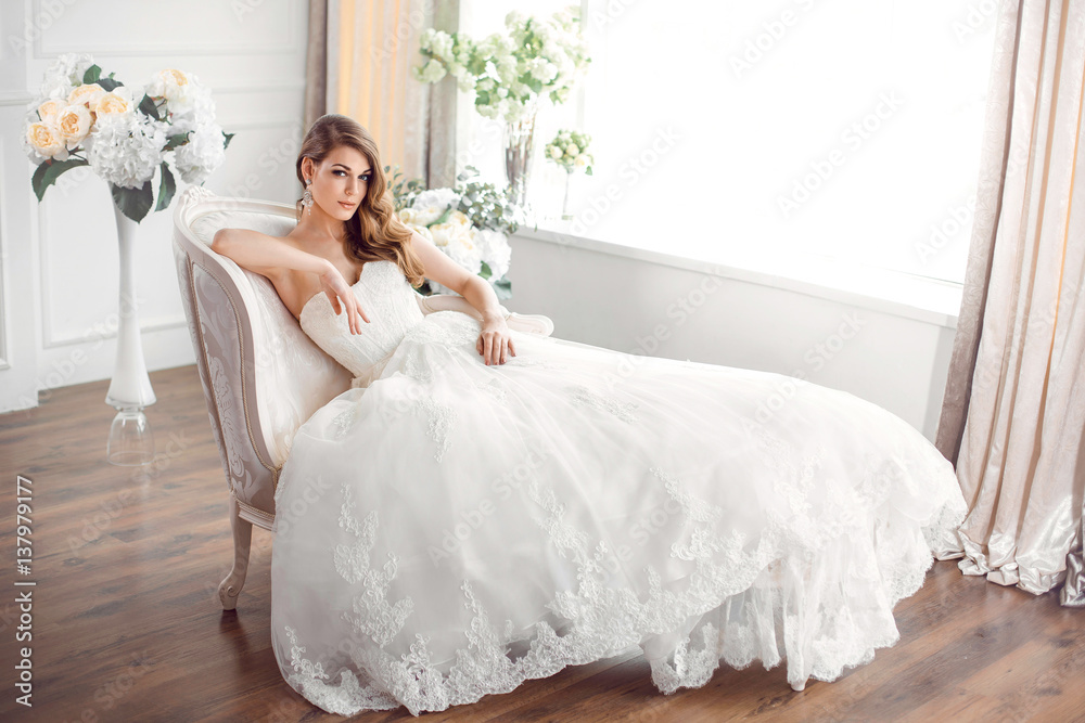 Bride in beautiful dress sitting resting on sofa indoors Bride in beautiful dress sitting resting on sofa indoors