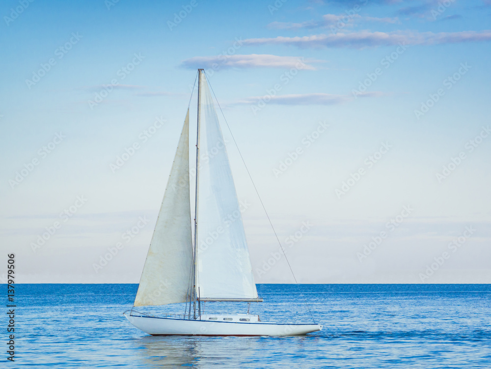 Sailing yacht with white sails in the open Sea. Blue water.