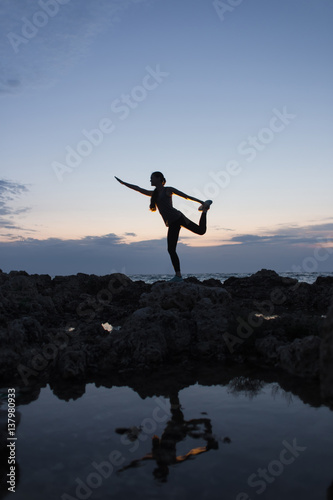 Silhouette of a girl in dancer pose at sunset near the sea