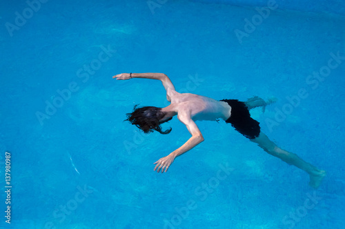 Young man floating and having fun in the pool