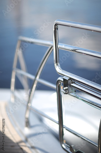 Shiny chrome metal fencing and railings yacht on the background of the smooth surface of the water