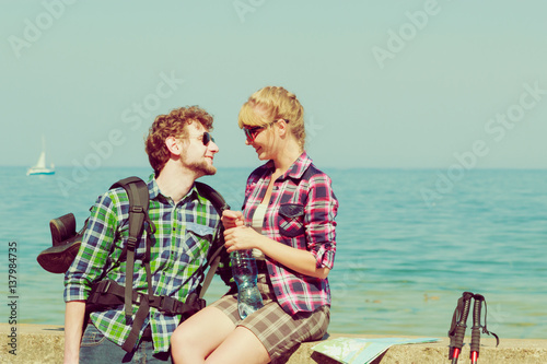 couple backpacker tramping by seaside