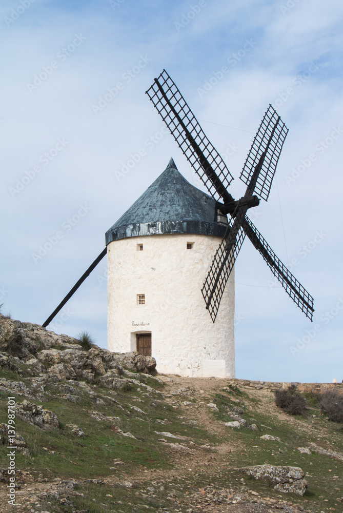 White old windmill on the hill near Consuegra (Castilla La Mancha, Spain), a symbol of region and journeys of Don Quixote (Alonso Quijano) on cloudy day.