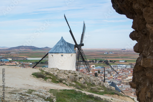 White old windmills on the hill near Consuegra (Castilla La Mancha, Spain), a symbol of region and journeys of Don Quixote (Alonso Quijano) and a town on cloudy day.