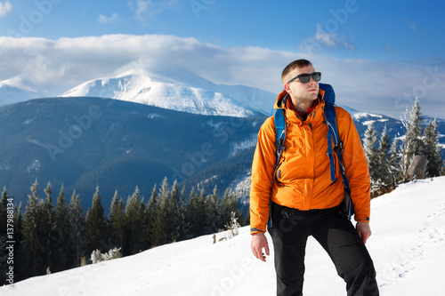 Hiker in winter mountains. Man with backpack trekking in mountains. Winter hiking
