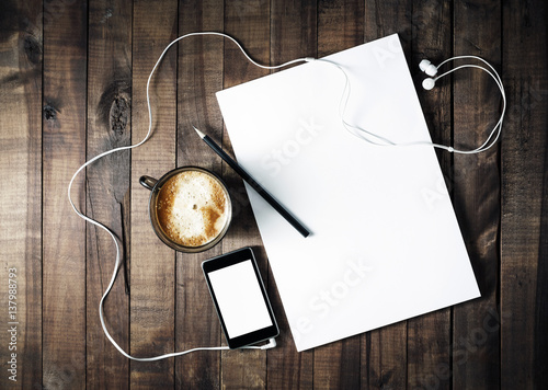 Photo of blank stationery on vintage wooden table background. ID template. Mockup for branding identity. Letterhead, coffee cup, phone, pencil and headphones. Blank objects for placing your design. photo