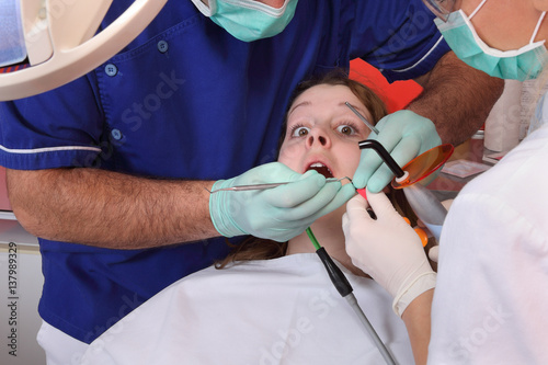 Dentist and nurse filling patient tooth  patient in panic