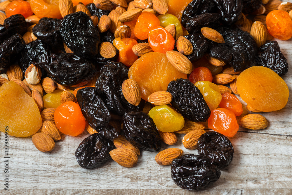 prunes, dried apricots, dried mandarins and almonds on a light wooden background prunes, dried apricots, dried mandarins and almonds on a light wooden background