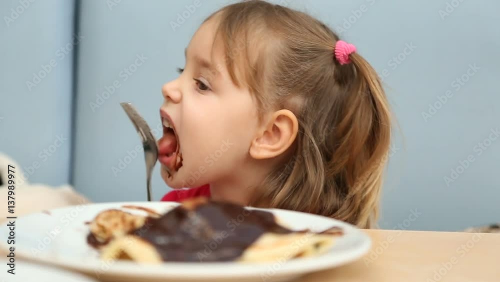 3-4 years old caucasian girl eating pancakes with chocolate. 3-4 years old caucasian girl eating pancakes with chocolate.