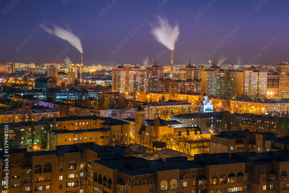 Night view of Voronezh from rooftop. Residential area and smoking pipes of factories 