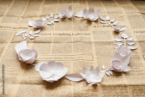 vintage frame with paper flowers on the old newspapper