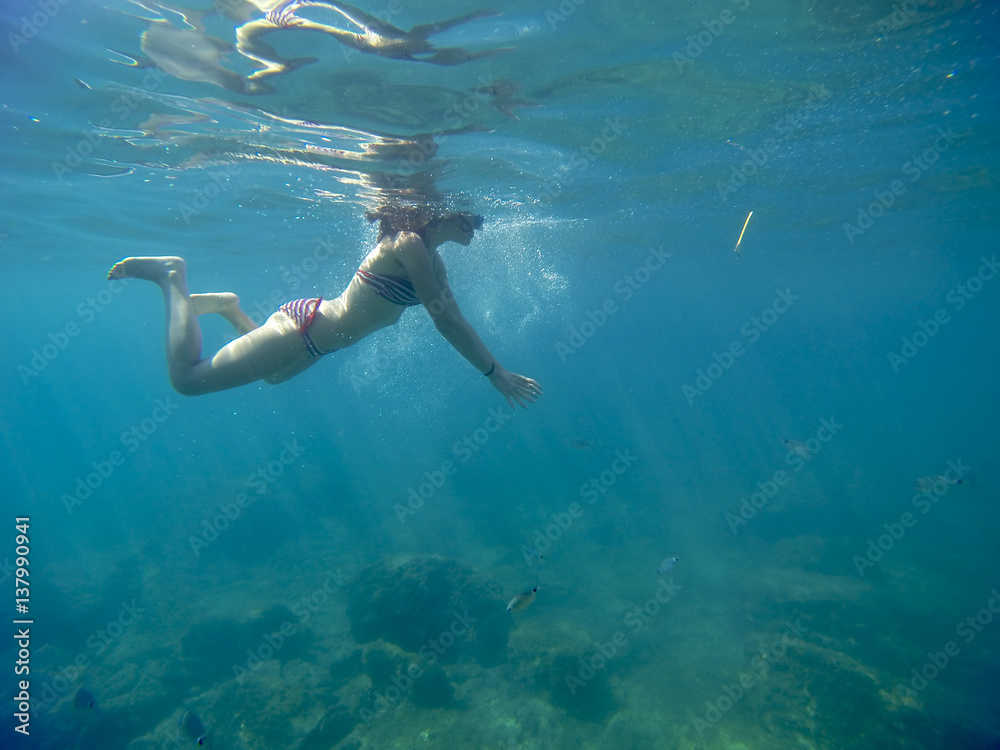 young woman swimming into the deep turquoise sea