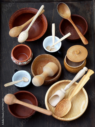 Ceramic, wooden, clay empty handmade bowl, cup and spoon on dark background. Pottery earthenware utensil, kitchenware.