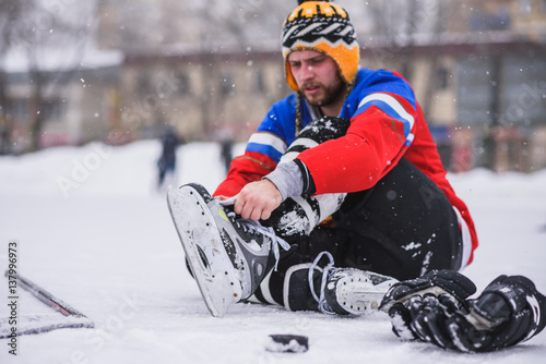 Photography hockey player sitting on the ice to tie shoelaces