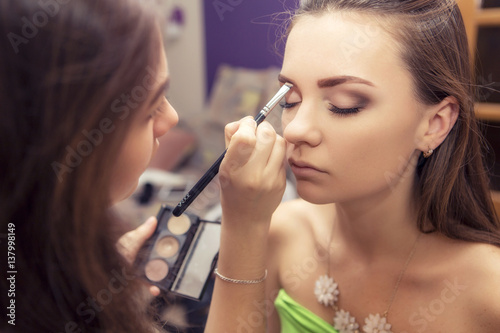 Brunette make up artist woman applying make up for a brunette bride in her wedding day