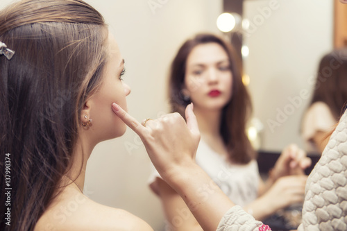 Make up artist teacher explaining l her student basic knowledge of how to apply make up properly on a brunette model girl. focus on a model girh and teacher