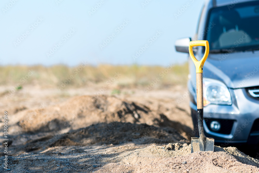 camp shovel on a background of sand stuck in car accident camp shovel on a background of sand stuck in car accident