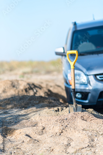 camp shovel on a background of sand stuck in car accident © markhipov