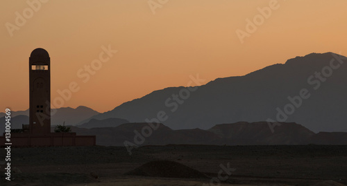Lonely minaret in the desert mountains at sunset.