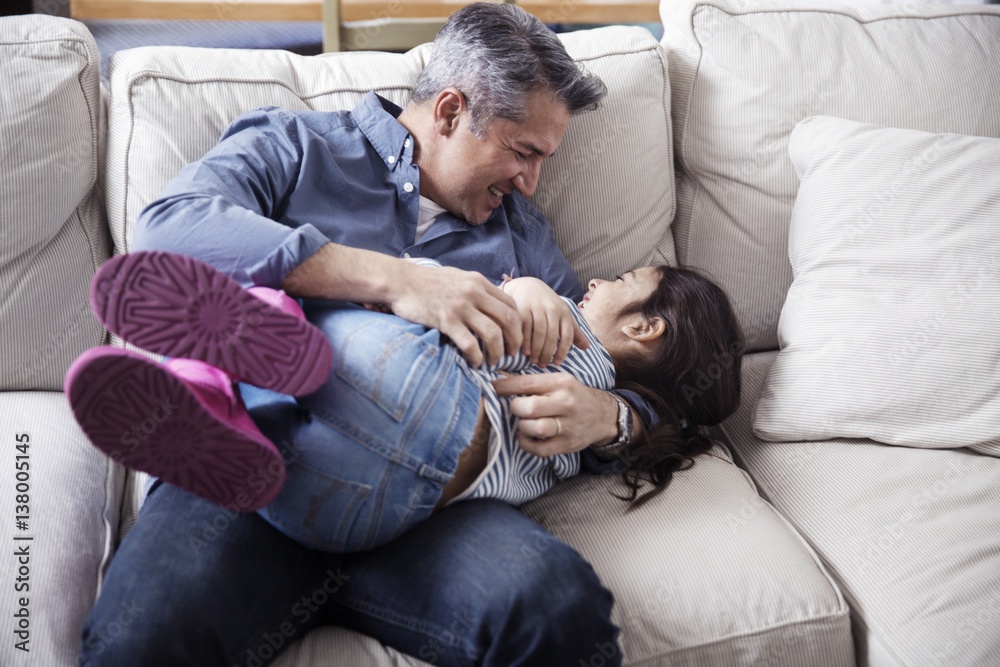 Cheerful Father and daughter enjoying on sofa at home Cheerful Father and daughter enjoying on sofa at home