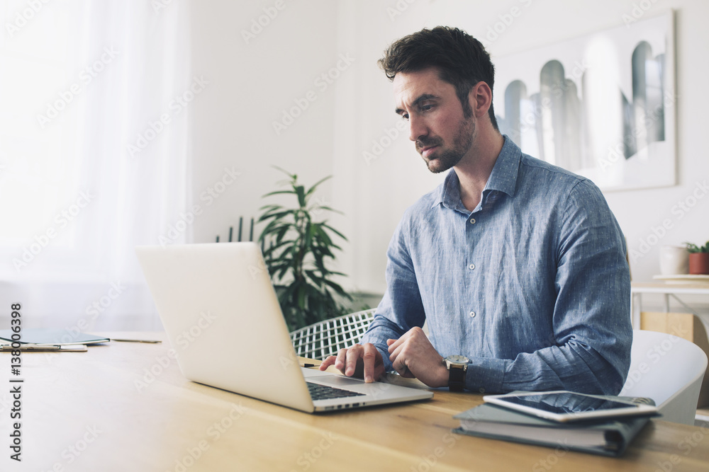 Businessman using laptop computer at desk in office Businessman using laptop computer at desk in office
