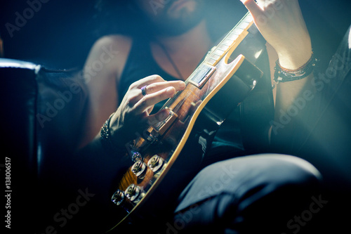 Midsection of musician practicing guitar in rock music studio photo