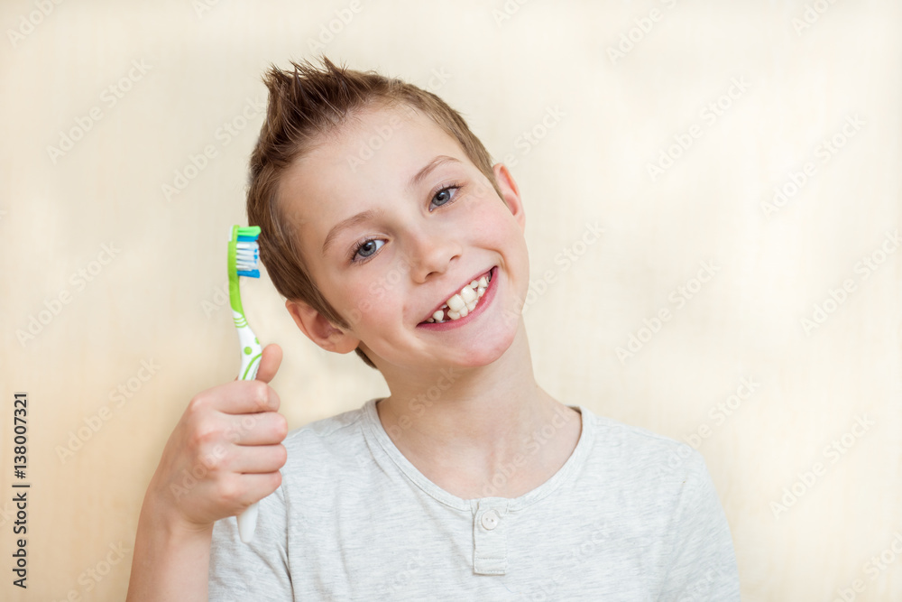 Cute boy shows his teeth and toothbrush. Light background Cute boy shows his teeth and toothbrush. Light background
