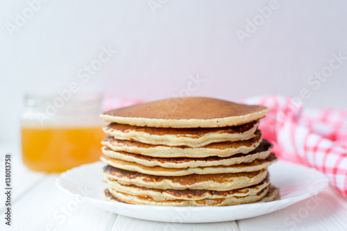 Healthy breakfast. Stack of delicious, homemade pancakes with honey, cherry and banana on white plate 