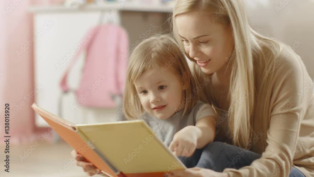 Beautiful Young Mother and Her Cute Little Daughter Read Children's Book Together. Children's Room is Pink and Full of Toys. Shot on RED EPIC-W 8K Helium Cinema Camera. Beautiful Young Mother and Her Cute Little Daughter Read Children's Book Together. Children's Room is Pink and Full of Toys. Shot on RED EPIC-W 8K Helium Cinema Camera.