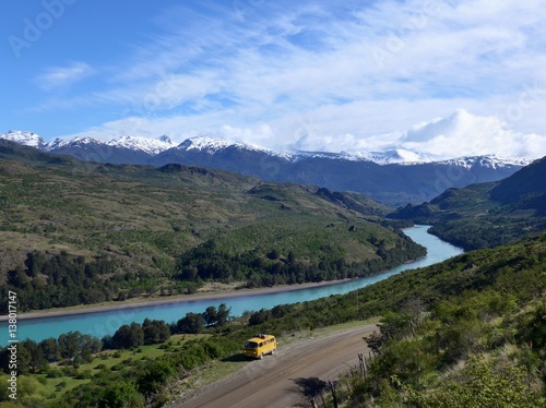 Yellow Kombie parked in front of the stunning backdrop of a turquoise river in the Mountains.