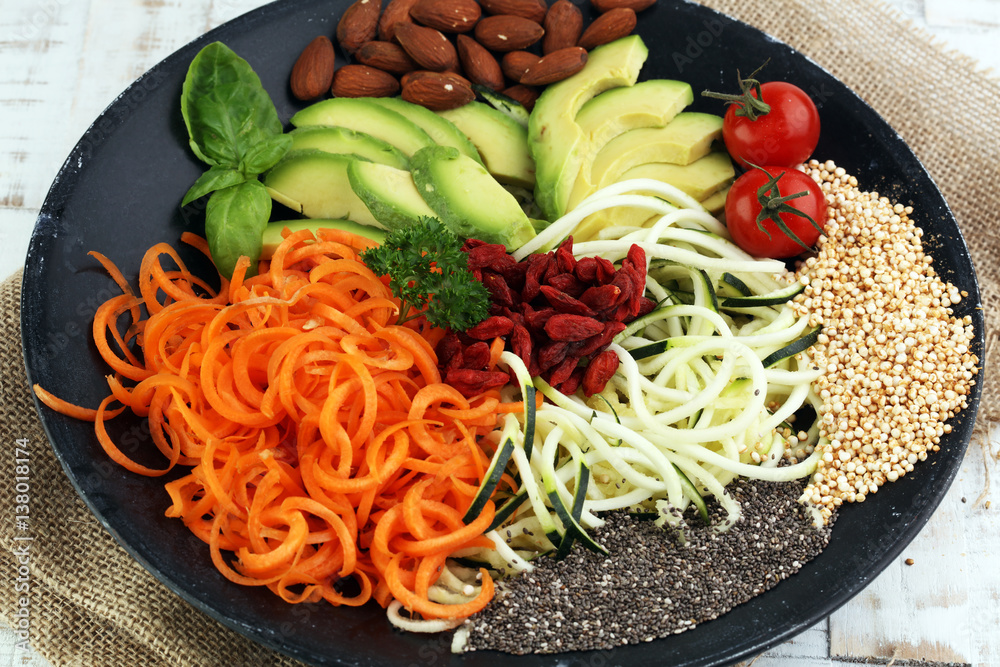 Φωτογραφία superfood: bowl with zucchini carrot noodles, avocado, goji and chia seeds on wo