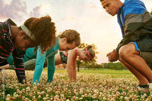 Photos Diverse group of women during a fitness training doing push-ups at sunset in nat
