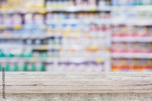 Abstract blur supermarket shelves background with wood table