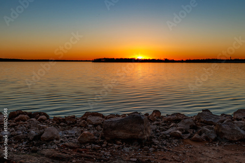 Lake sunset with foreground of rocks.