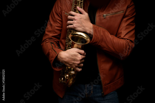 musician saxophone player holding his saxophone on isolated black background.