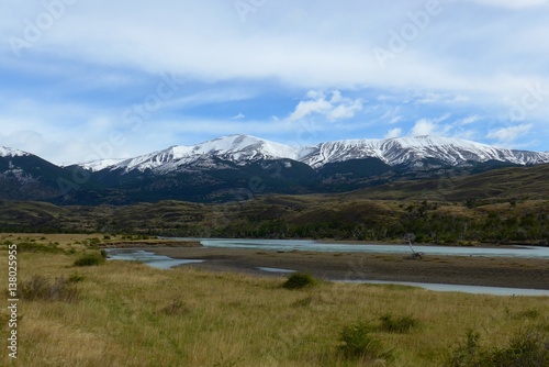 Fresh snow melt stream flowing through a beautiful open meadow surrounded by snow capped mountains in Torres del Paine National Park. 