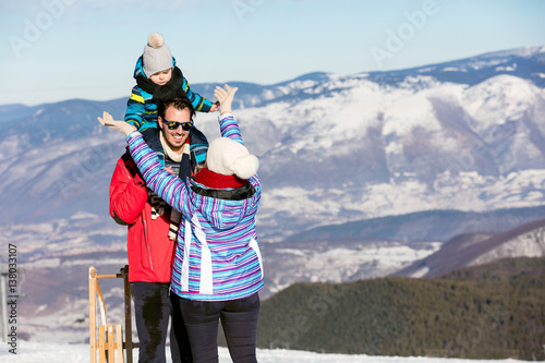 Father, mother and children are having fun and playing on snowy winter walk in nature.