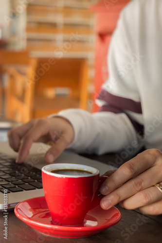Hand on red cup of espresso