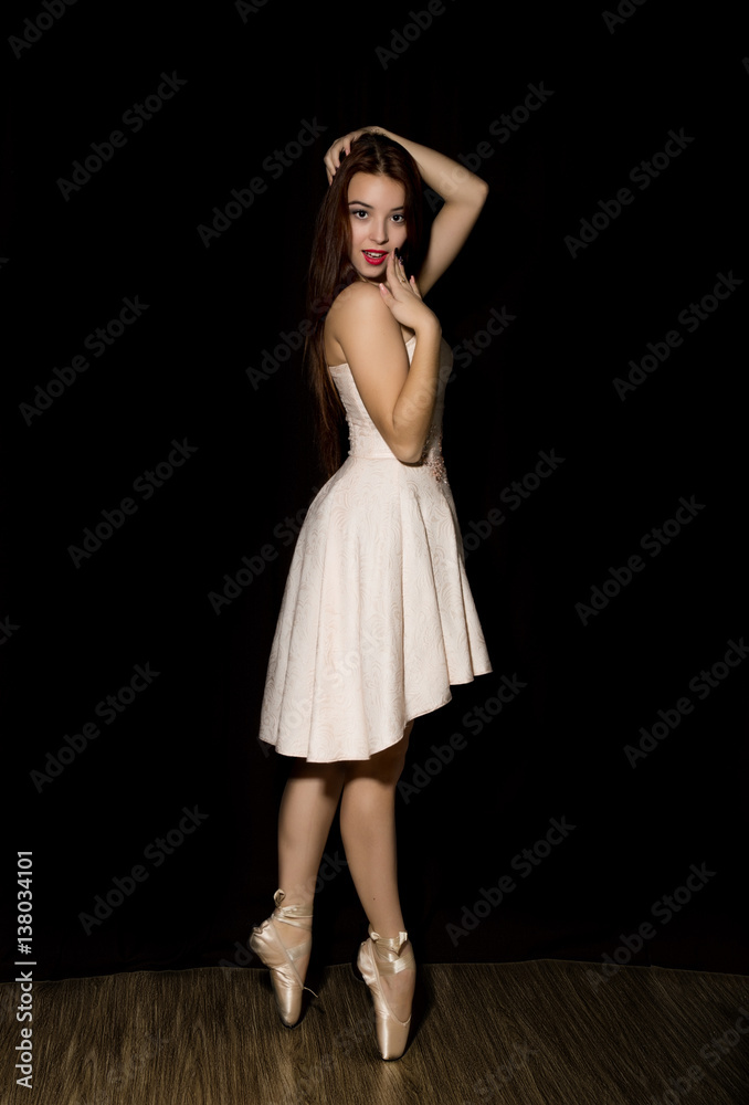 Young ballerina with a perfect body is dancing in pointe shoes on dark background Young ballerina with a perfect body is dancing in pointe shoes on dark background