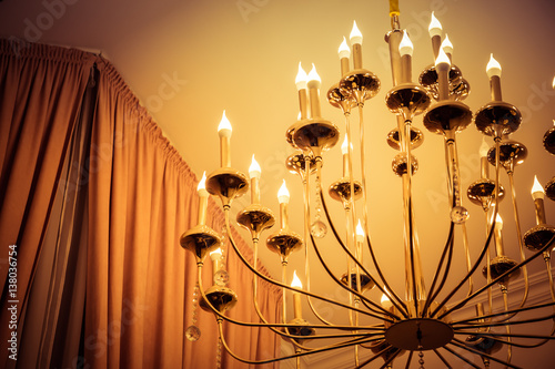 Chandelier with candles under the ceiling.
