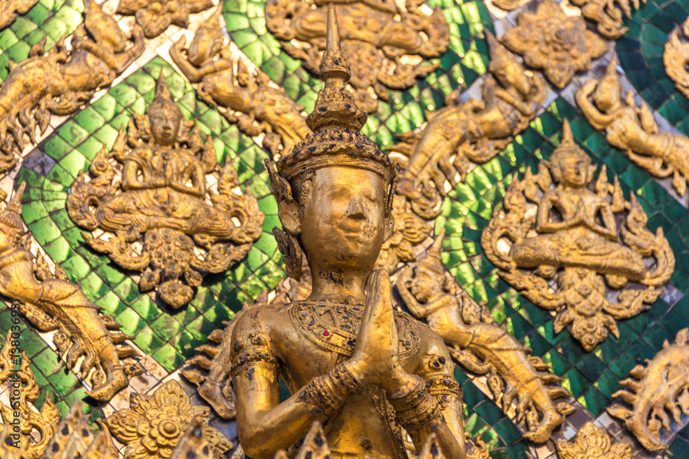 Close up of golden figurine in wall decoration of Temple of Emerald Buddha