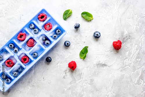 blueberry and raspberry in icetray on stone background top view mock-up photo