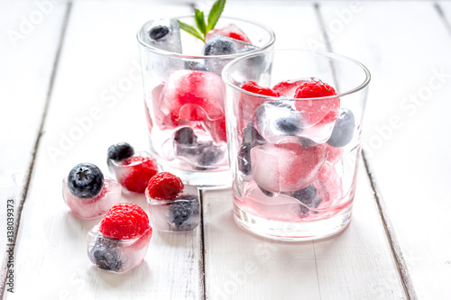 Frozen berries in glass for cocktail on wooden table background