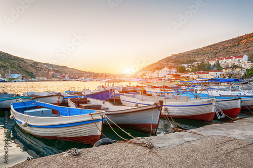 Sailing boats and yachts anchored in calm bay at sunset