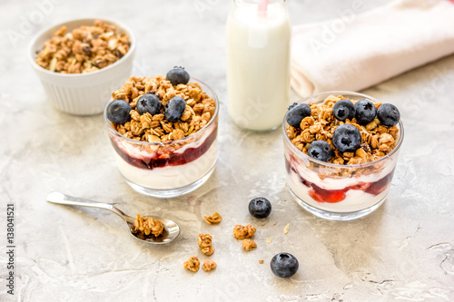 Morning granola in glass with yogurt, honey and milk on white desk
