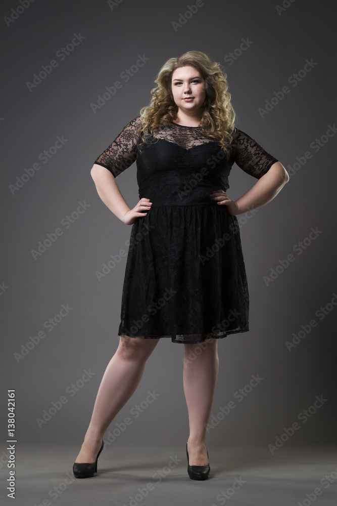 Young beautiful plus size model in black dres, xxl woman on gray studio background Young beautiful plus size model in black dres, xxl woman on gray studio background
