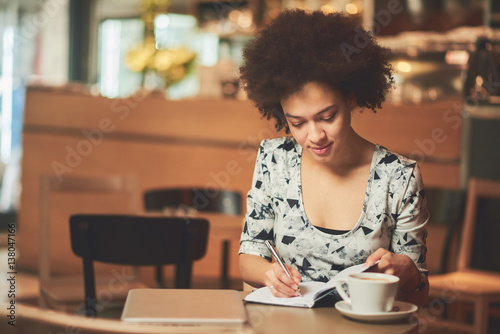 Mixed race woman in coffee shop having cofe and smiling